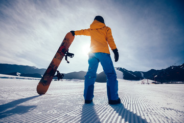 one snowboarder with snowboard looking at the  snowobard piste on winter mountains