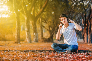 young man listening to music with headphones from mobile in park