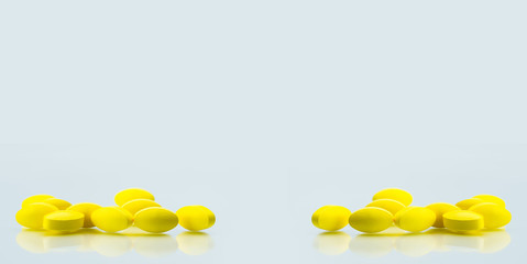 Yellow oval tablet pills with shadows on white background with copy space for text. Mild to moderate pain management. Pain killer medicine.
