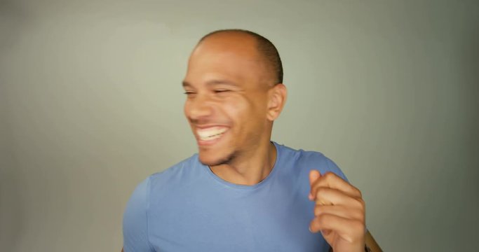 4K Happy laid-back man with a great smile dancing & interacting with camera on plain background
