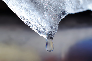 Naklejka na ściany i meble Drop of water hanging from ice chunk