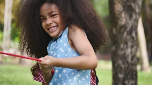 A little girl playing tug of war with her friends in a park