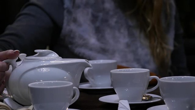 Woman pours herbal tea in a white cup in cafee. slow motion