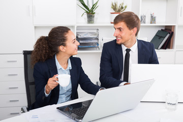 young man and cheerful woman coworkers talking in firm office
