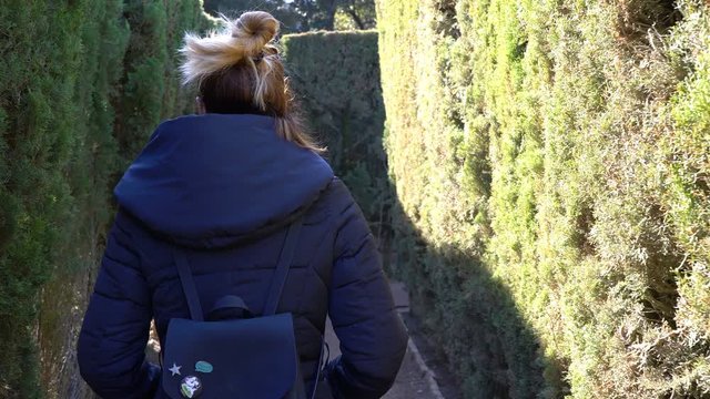 Woman walking through a hedge maze on a sunny winter day