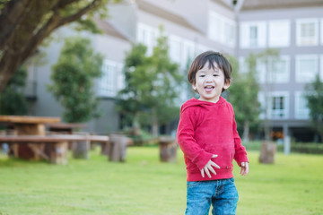 Fototapeta premium Closeup happy asian kid stand on grass floor in the garden background with fun motion