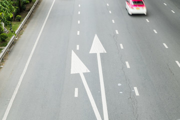 surface old and pale white painted arrow sign on cement road textured background