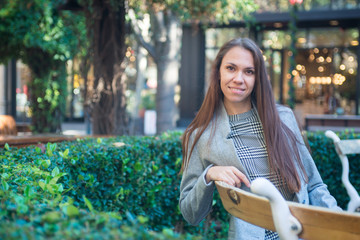 Smiling happy woman sitting on the bench in the city