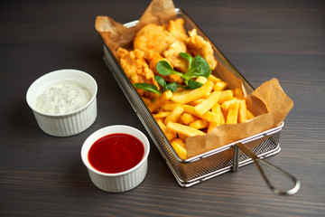 chicken nuggets with french fries and different sauces on wooden board,