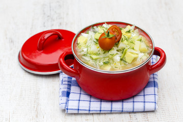 Red saucepan with okroshka - traditional summer soup in Ukraine, Belarus and Russia. Close up