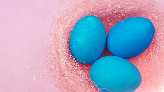 Easter color blue eggs in pink pastel nest on rose background. 