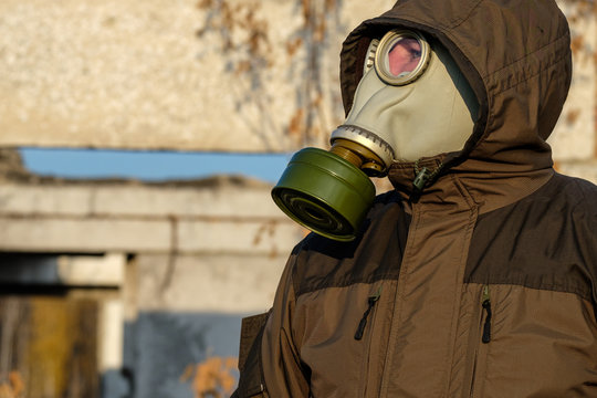 assessing the danger of a man in a gas mask looking into the distance, gas mask green and the same suit, autumn