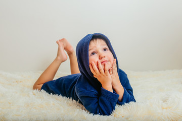 the baby in the blue robe and hood lies on fluffy blanket