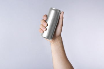 Male hand with aluminum can on light background