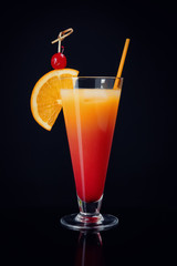 Glass of Sex on the Beach cocktail against black background