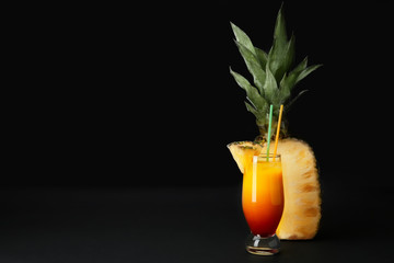 Glass of Sex on the Beach cocktail and fresh pineapple against dark background