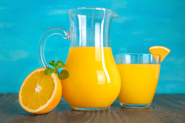 Jug and glass of fresh orange juice on wooden table