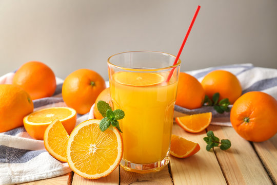 Glass of fresh orange juice with fruit on wooden table
