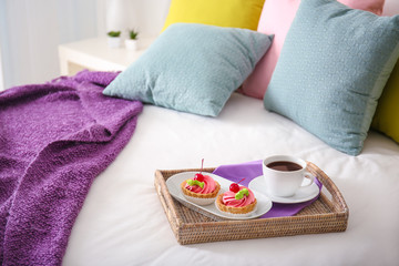 Tray with tasty breakfast on comfortable bed at home