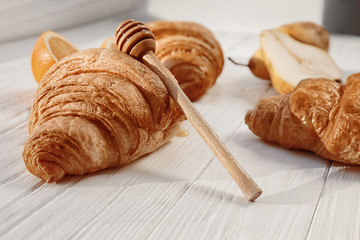 Tasty croissants with honey on wooden table