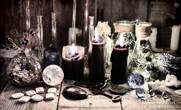Black candles with runes, crystals, old key, healing herbs and magic ritual objects Halloween, occult, esoteric and wicca concept. Vintage background
