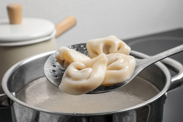 Cooked dumplings on skimmer over saucepan