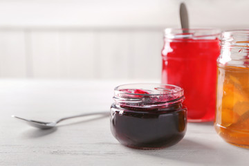 Jars with sweet jams on table