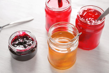 Jars with sweet jams on table