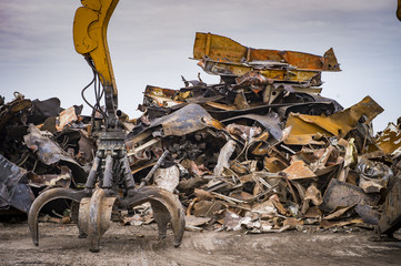 Large tracked excavator working a steel pile at a metal recycle yard - obrazy, fototapety, plakaty