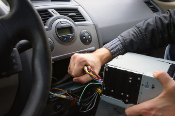 Male hands remove audio system from car dashboard. Automobile receiver disconnecting and removing