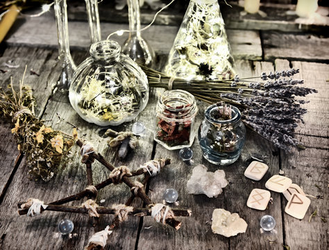 Magic ritual objects, wooden pentagram, ancient runes, bottles and herbs. Halloween, occult, esoteric and wicca concept. Vintage background