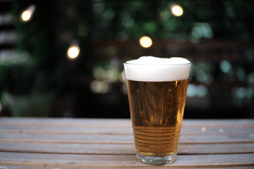 Beer on wood table in garden background. Selective focus