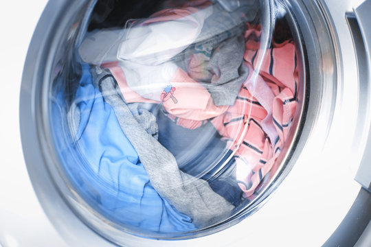 Laundry Machine At Work, Closeup Of Washing Machine Door With Spinning Laundry.