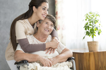 Caring and smiling woman hugging happy grandmother