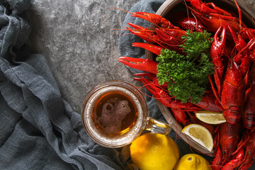 Delicious boiled crayfish close-up, lemon and parsley with beer. Dark background. Dinner with seafood. - obrazy, fototapety, plakaty