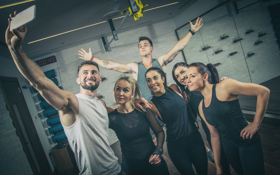 Group of sporty people in sportswear taking selfie photo at gym.