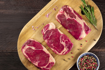 Three slices of raw meat on rustic textures with seasoning