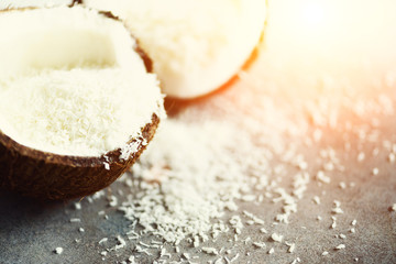 Coconut fuit halves with coconut shavings on grey concrete background. Copyspace