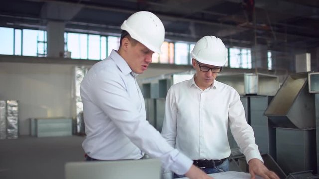 Two engineers are working on a desktop computer in a factory. slow-motion. Air ducts for conditioning and ventilation & fire extinguishing pipes at an industrial facility.