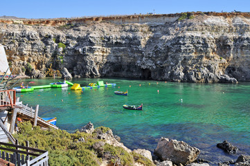 Bay of the island of Gozo with rocks and turquoise sea and playing with people