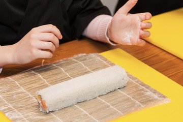 Children prepare sushi rolls. Master-class in the restaurant. Selective focus
