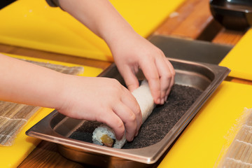 Children prepare sushi rolls. Master-class in the restaurant. Selective focus