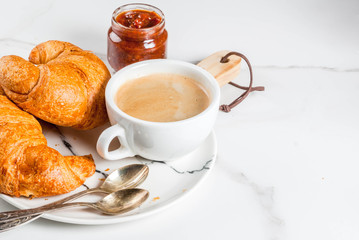 Homemade continental breakfast, coffee croissants. jam on white marble table, copy space
