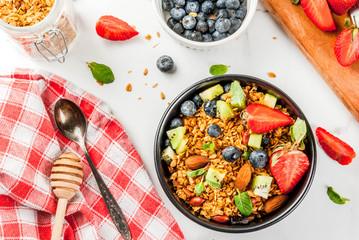 Healthy breakfast with muesli or granola with nuts and fresh berries and fruits - strawberry, blueberry, kiwi, on white table, copy space top view