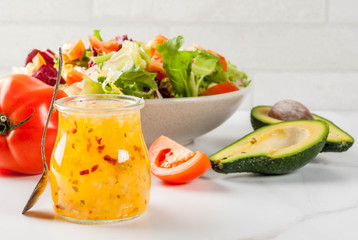 Classic Italian vinaigrette salad dressing, with fresh vegetables on white marble table, copy space