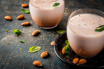 Traditional Indian beverage, Holi festival food, Thandai Sardai milk drink with nuts, spices, mint. Dark blue background, copy space
