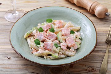 pasta italiana penne con salmone e panna su sfondo tavolo di cucina