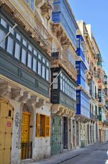 a narrow street with picturesque and colorful tenement houses in Malta