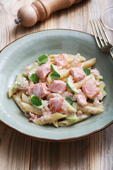 pasta italiana penne con salmone e panna su sfondo tavolo di cucina