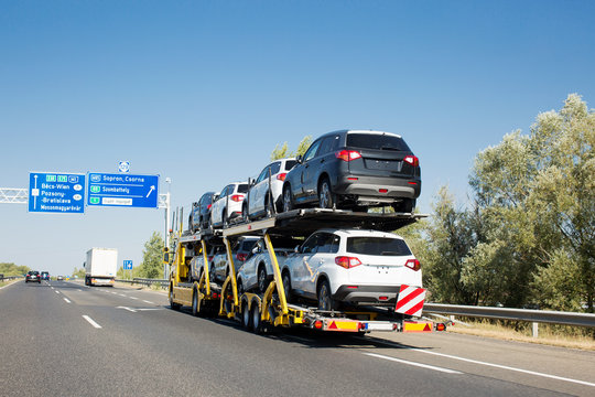 Car carrier trailer with new cars for sale on bunk platform. Car transport truck on the highway